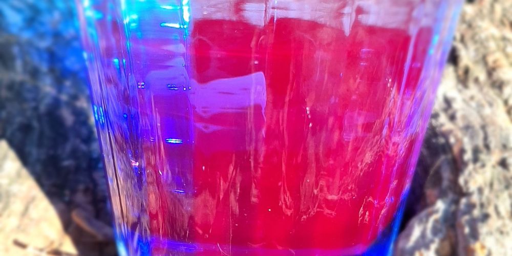 un verre de phycocyanine qui montre tout son spectre colorimétrique