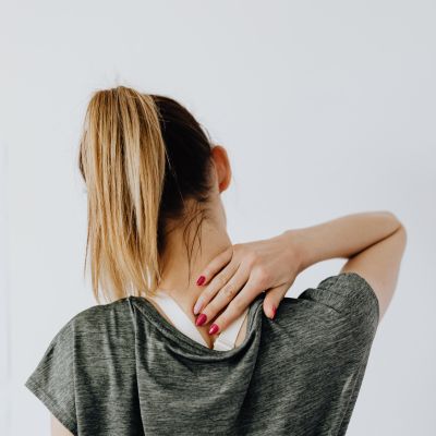 une femme touche sa nuque qui lui fait mal