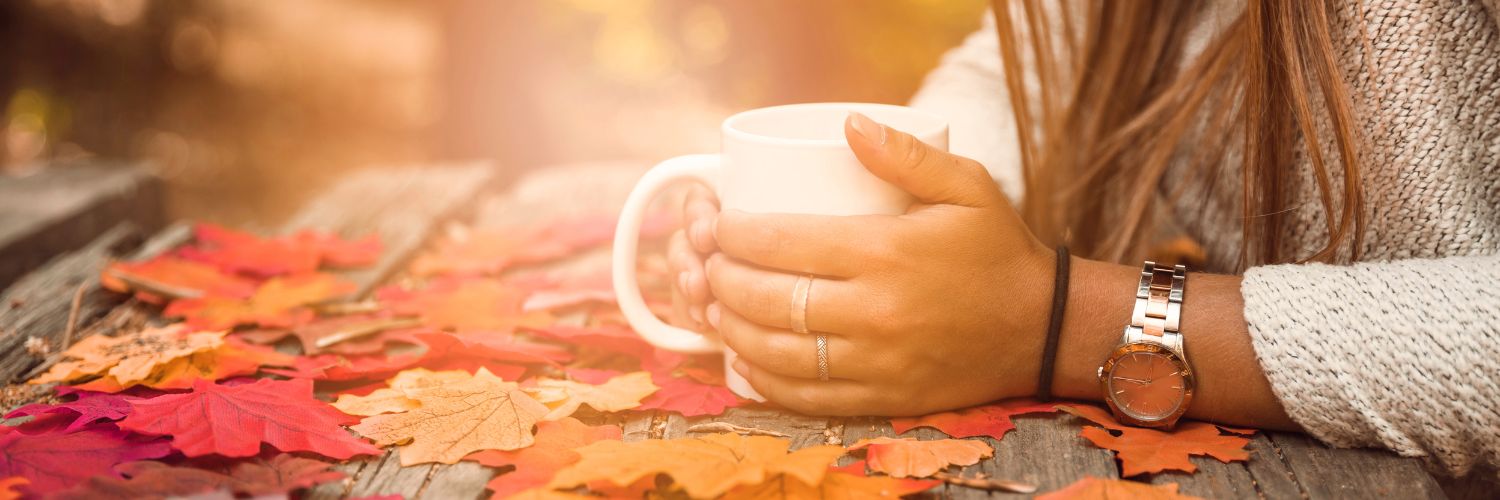 une femme tient une tasse de tisane chaude au coeur de la fôret